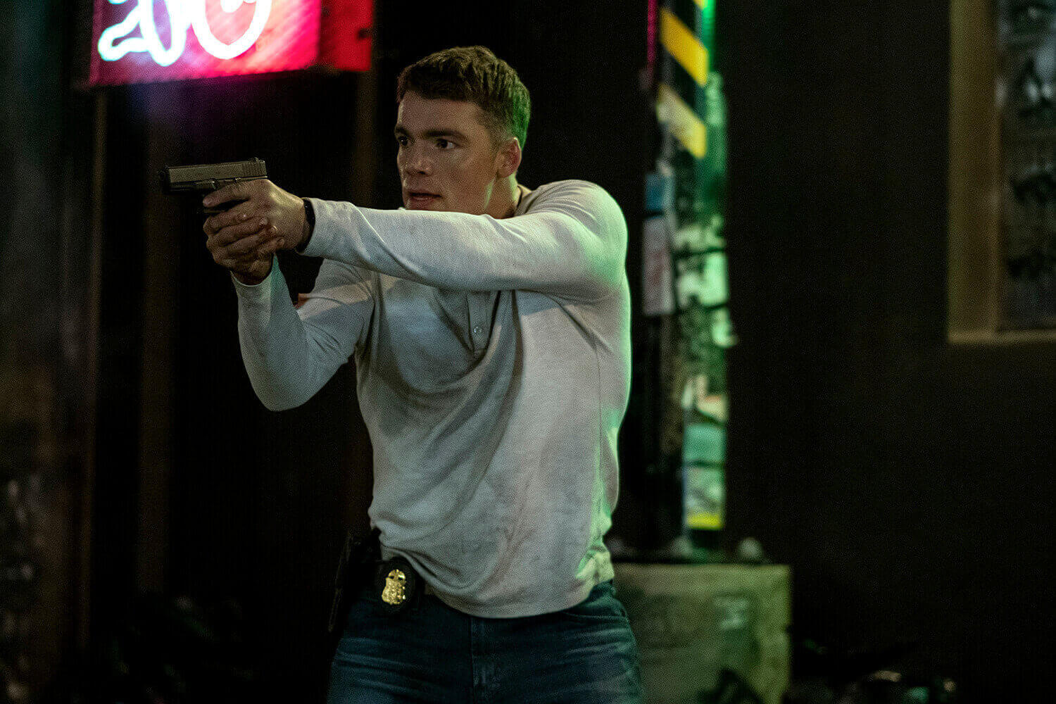 Gabriel Basso as Peter Sutherland holding up a gun in The Night Agent