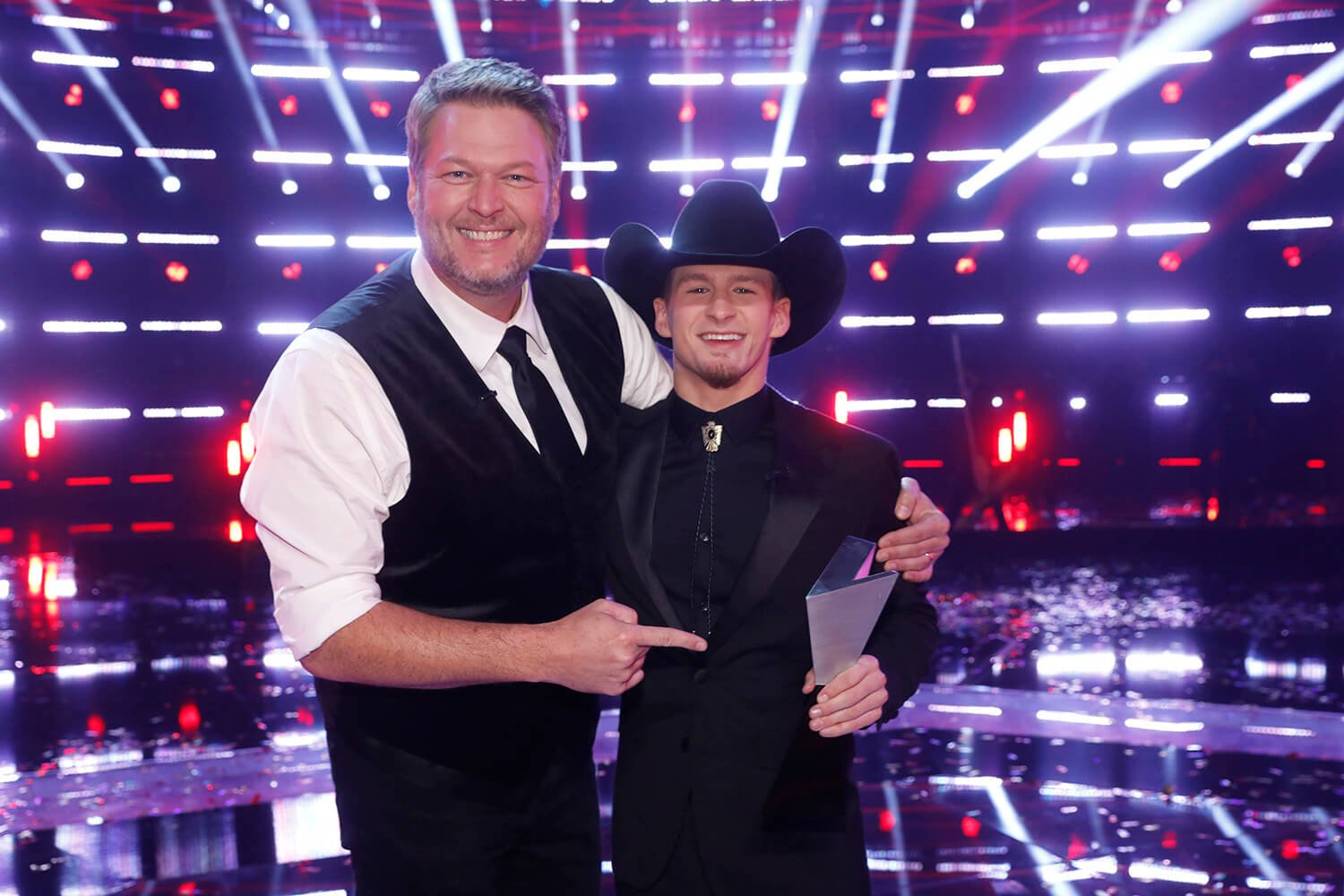Blake Shelton hugs and points to Bryce Leatherwood as Bryce holds the winning trophy on The Voice Season 22
