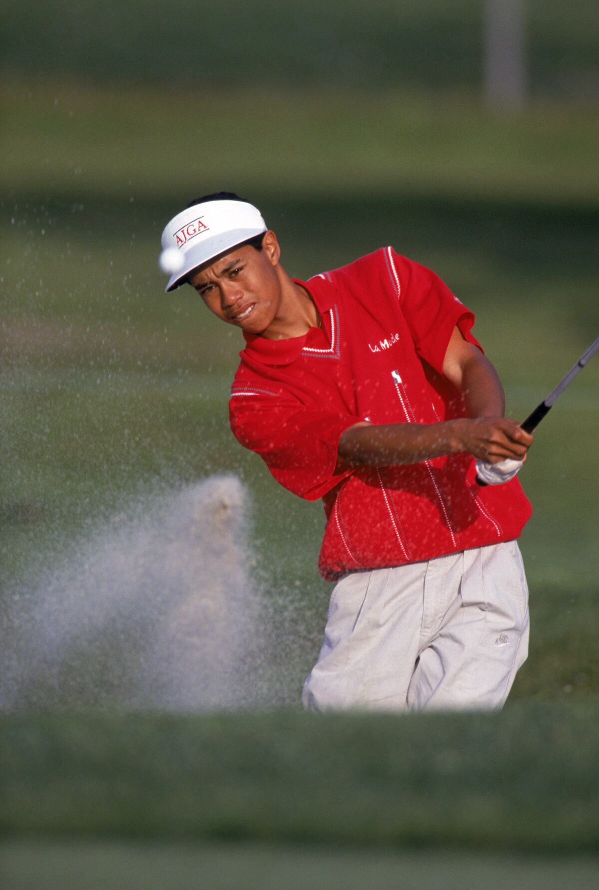 Tiger Woods, wearing a red shirt, golfs during a 1992 tournament. He was just 16 years old.