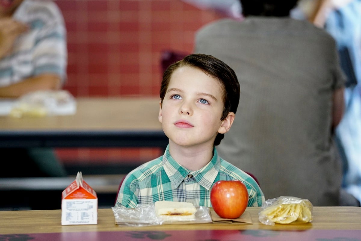 Iain Armitage as Sheldon Cooper wears a green shirt in the lunchroom during an episode of 'Young Sheldon'