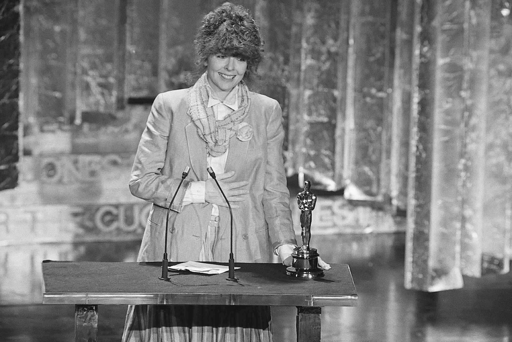 'Annie Hall' Diane Keaton with her Oscar in a black-and-white picture with her hand over her stomach and a smile on her face.