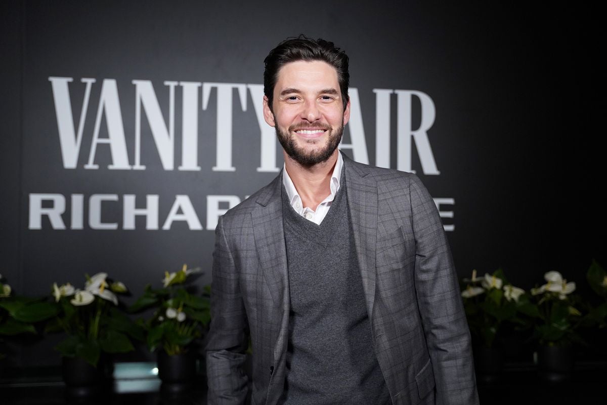 Ben Barnes smiles in front of the Vanity Fair logo.