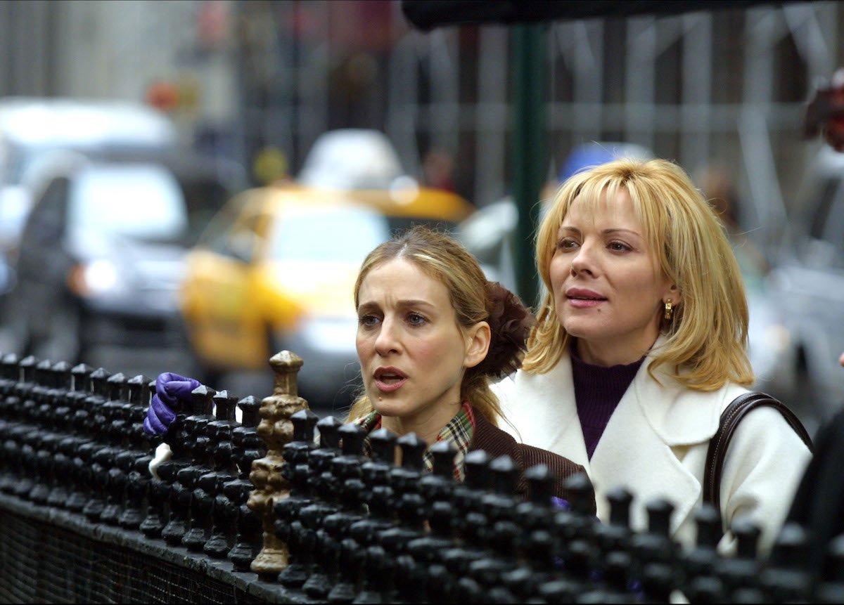 Sarah Jessica Parker and Kim Cattral during Filming "Sex and the City" looking over a black gate