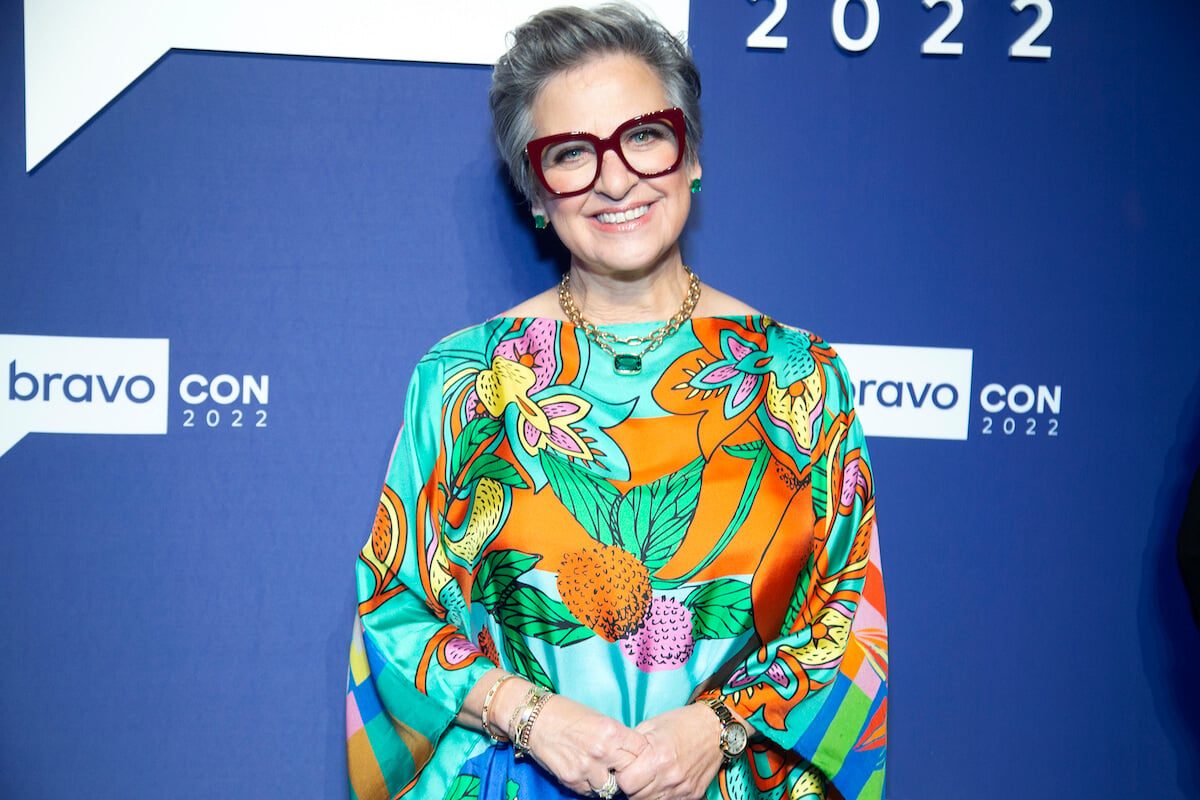 "RHONJ" star Caroline Manzo poses in a colorful floral dress and glasses at an event.