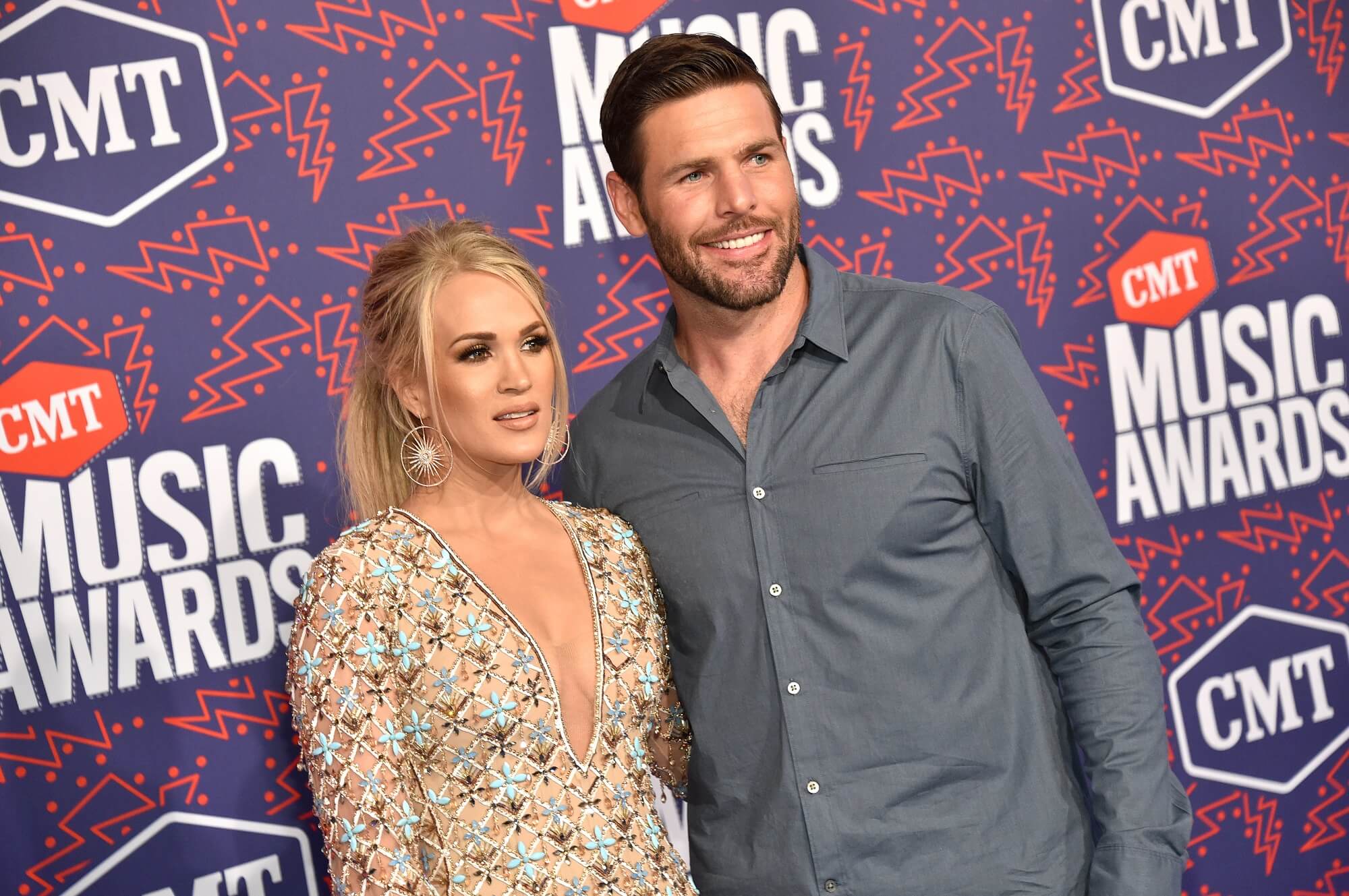 Carrie Underwood and Mike Fisher stand arm-in-arm in front of a backdrop that reads 'CMT Music Awards'
