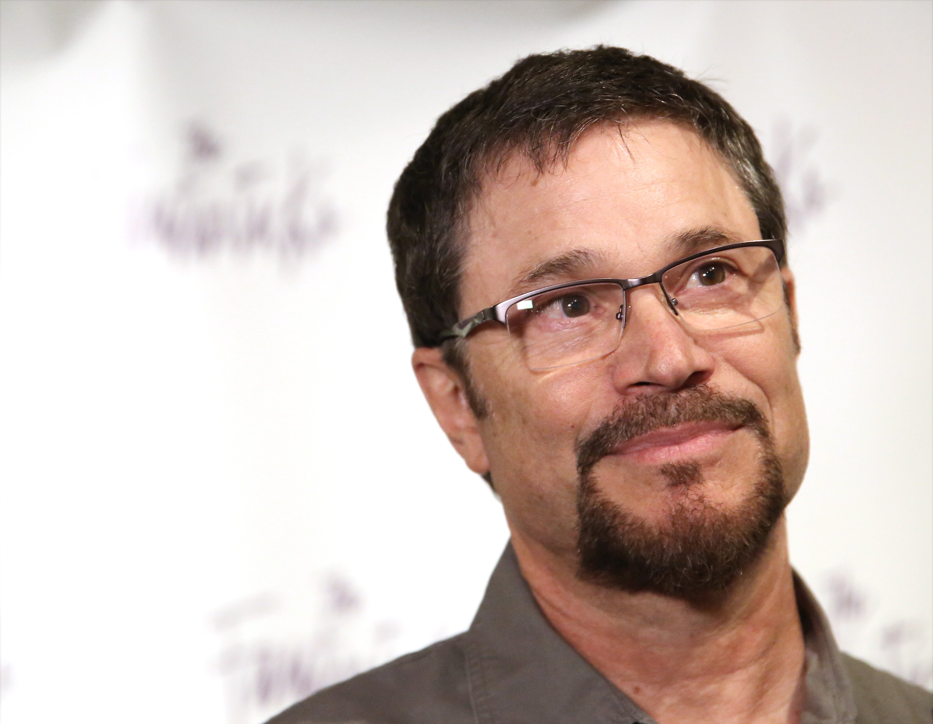 'Days of Our Lives' star Peter Reckell in a grey shirt and glasses; posing on the red carpet.