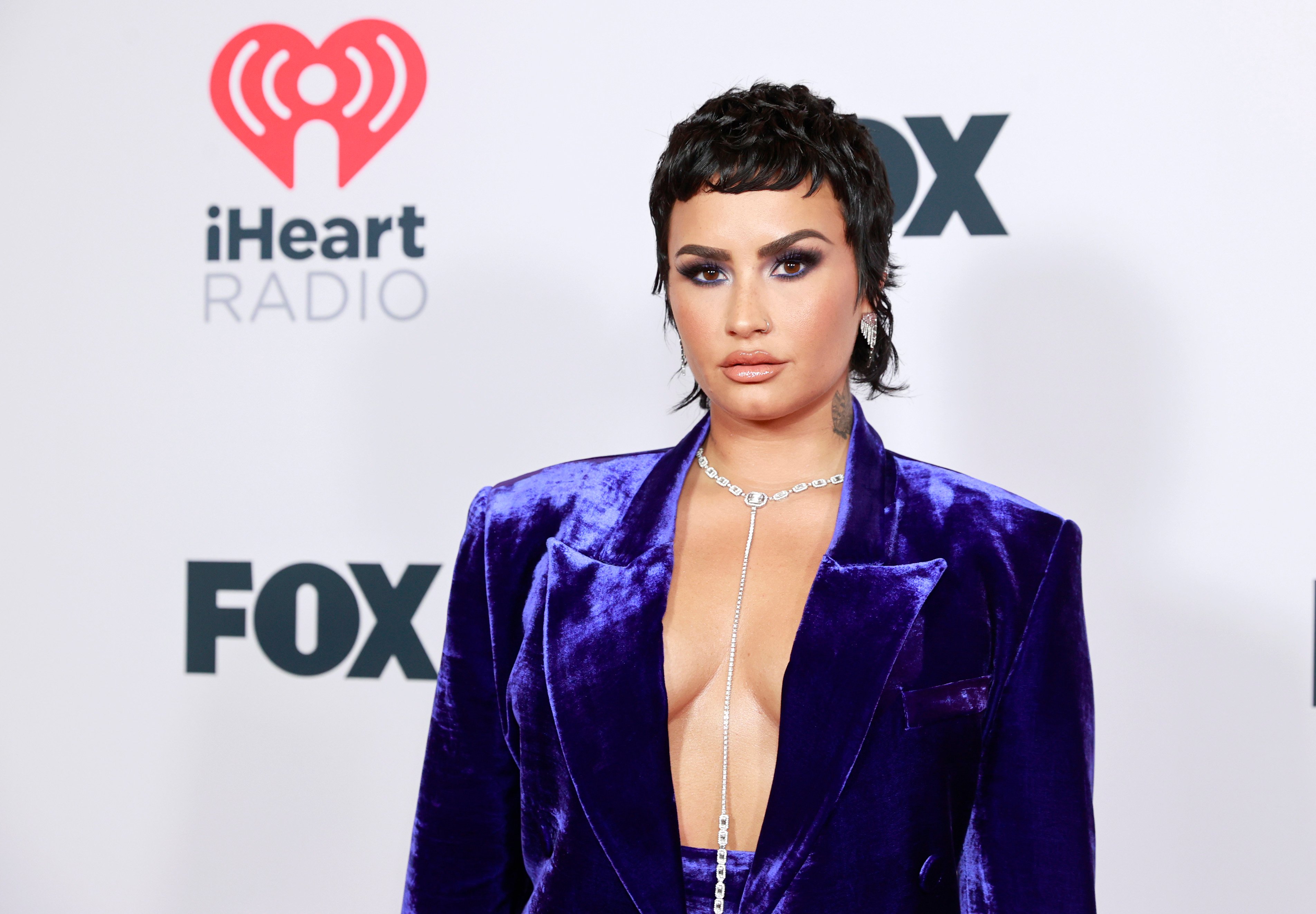 Demi Lovato posing for a picture in a purple suit.