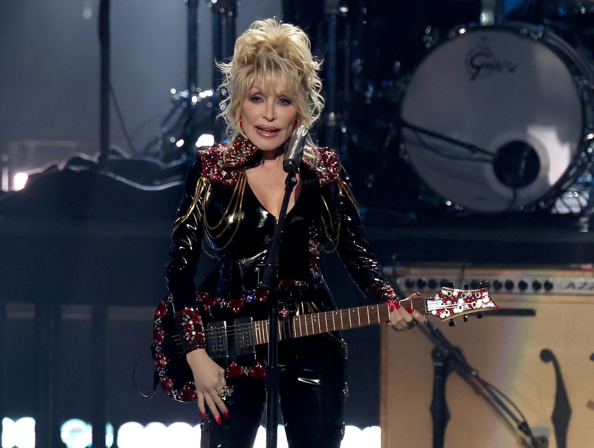 Dolly Parton performs onstage with an electric guitar.
