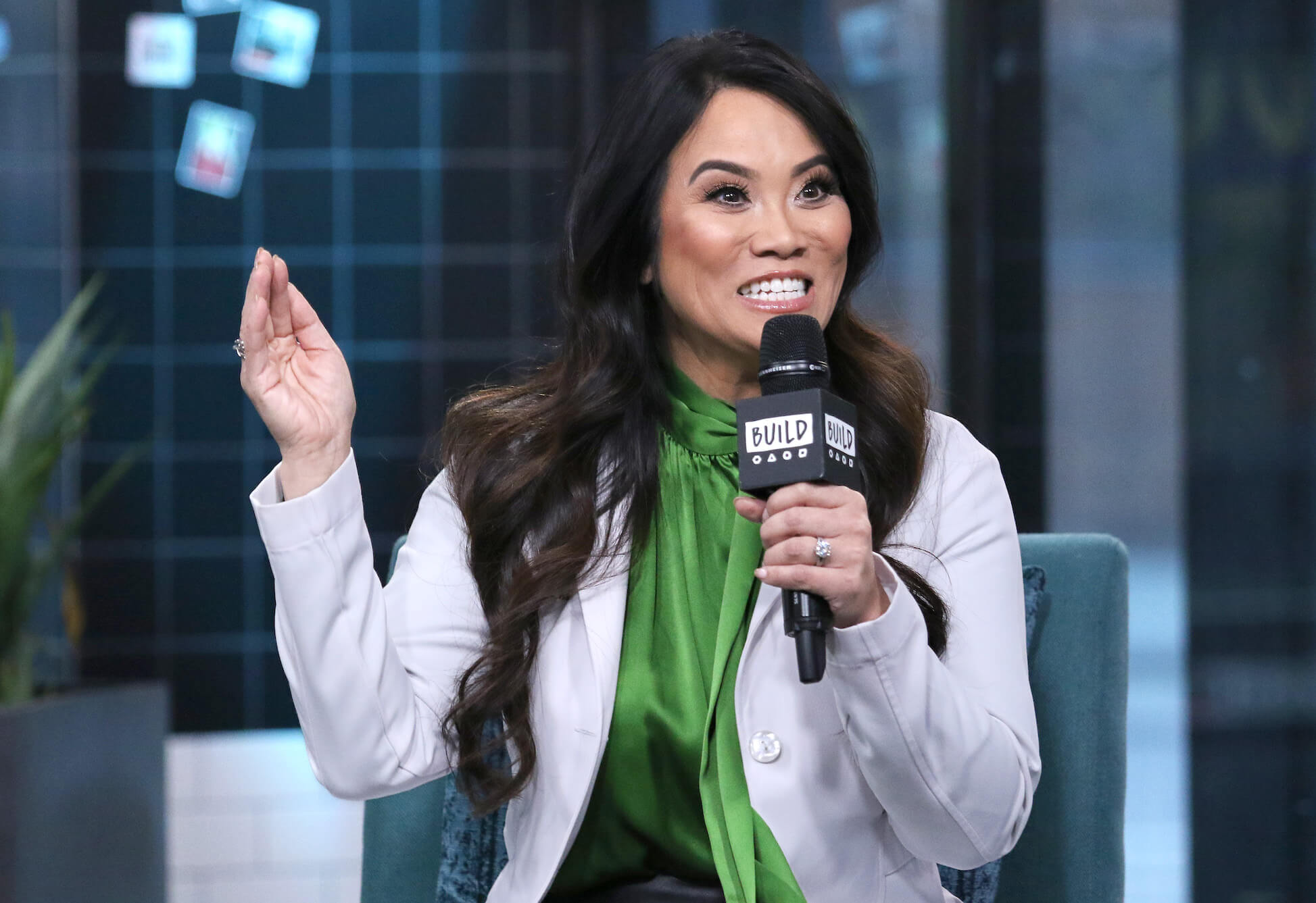Dr. Sandra Lee from 'Dr. Pimple Popper' smiling and holding a microphone to her mouth