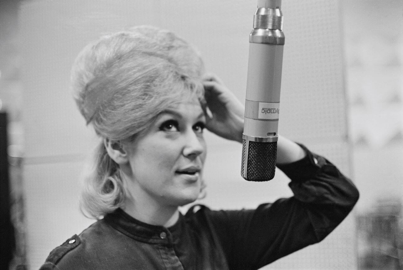 A black and white picture of Dusty Springfield standing in front of a microphone.