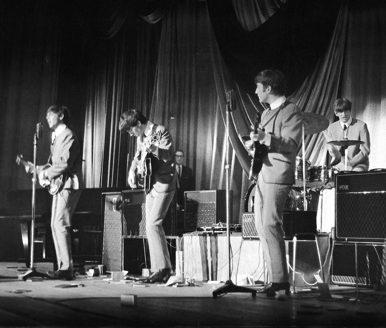 The Beatles performing in grey during a concert in 1963.