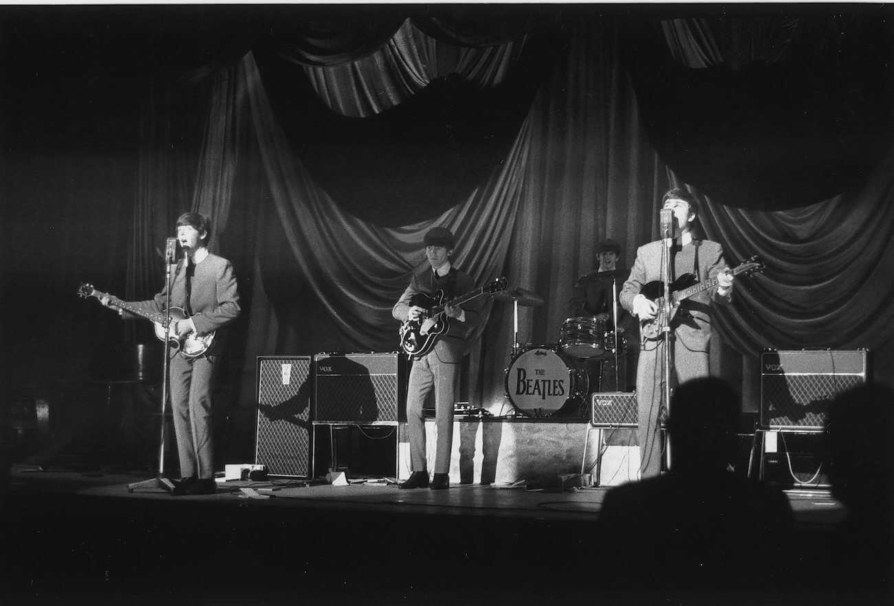 The Beatles performing in grey during a concert in 1963.