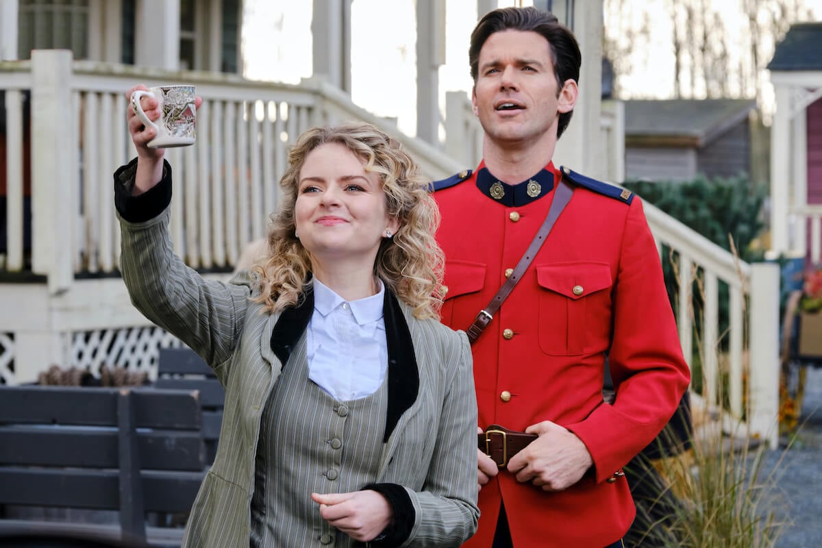 Faith (Andrea Brooks), waving, standing in front of Nathan (Kevin McGarry) in a mountie uniform in 'When Calls the Heart' Season 9