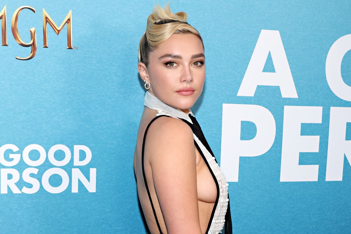 Florence Pugh poses in front of a blue backdrop.