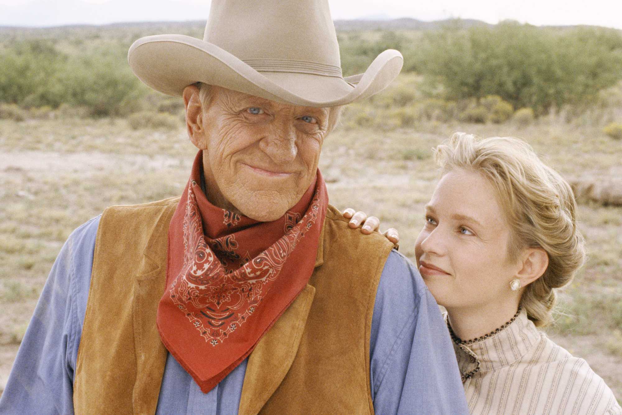 'Gunsmoke: One Man's Justice' James Arness as Matt Dillon and Amy Stoch as Beth Readon. Matt is smiling, wearing a Western outfit, while Beth is holding onto his arm and resting her head on his shoulder, looking up at him.