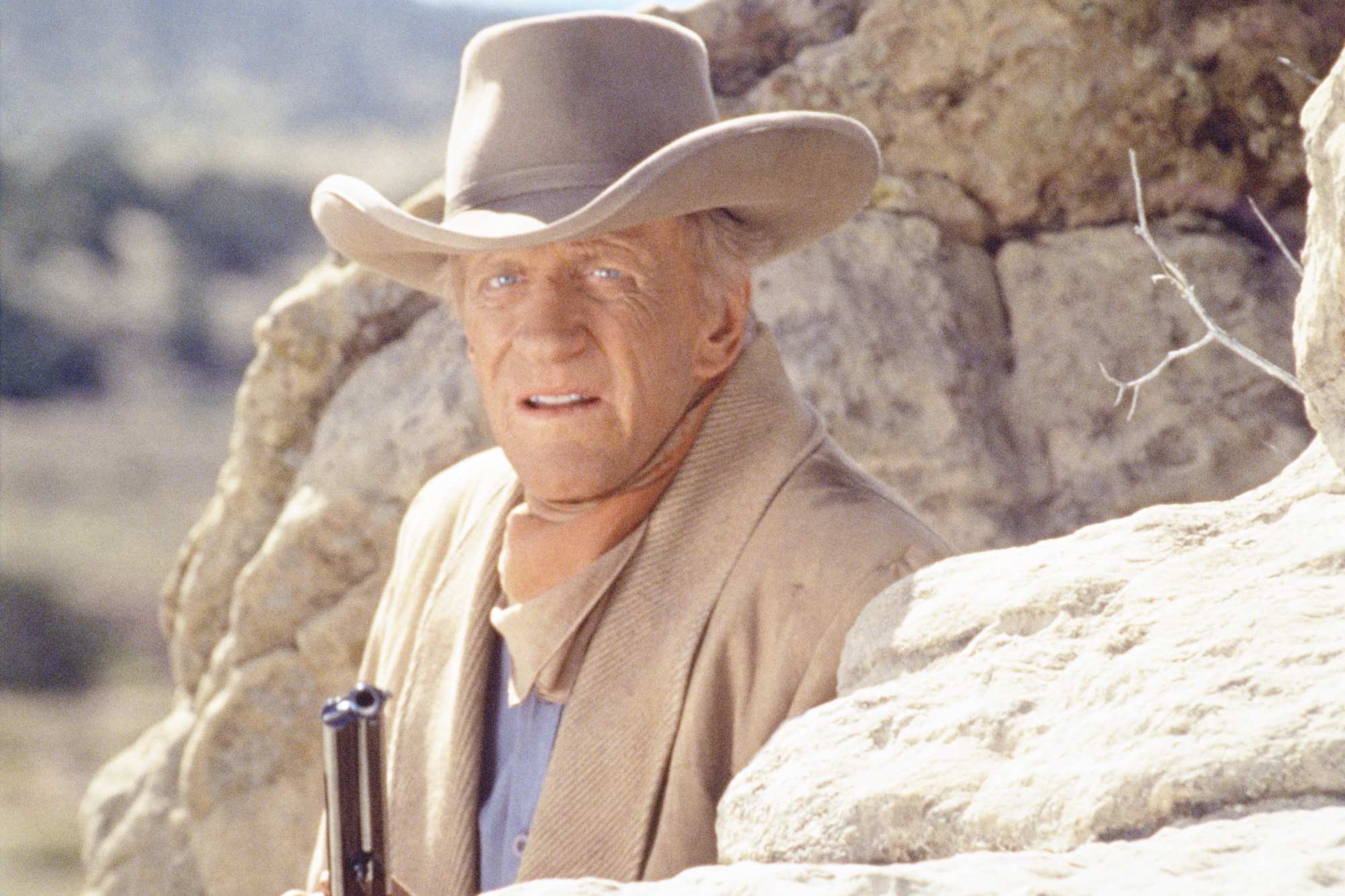 'Gunsmoke: One Man's Justice' James Arness as Matt Dillon hiding behind a rock, holding a gun. He's wearing his Western costume.