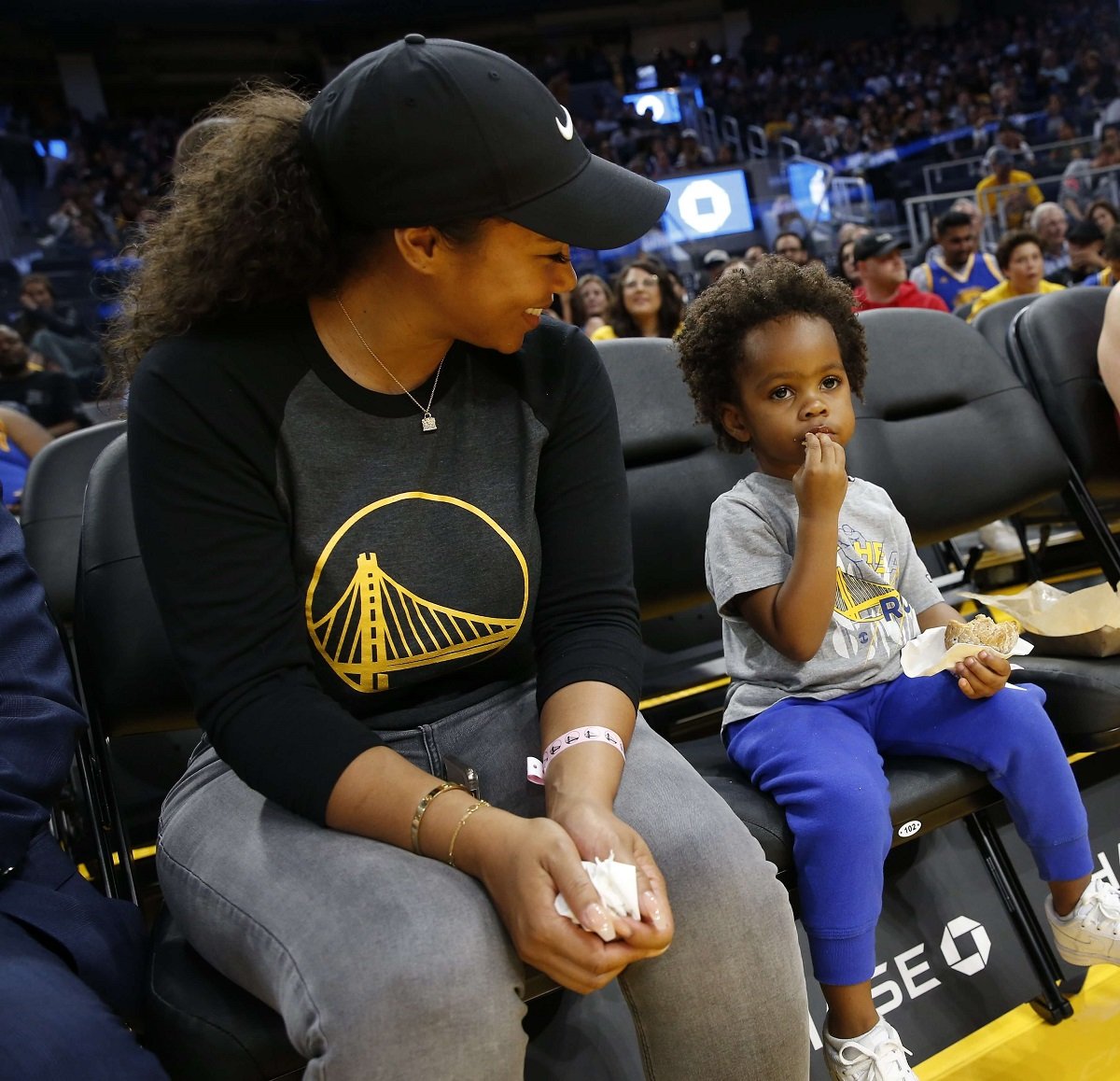 Hazel Renee sitting courtside at a Golden State Warriors game with her daughter Olive