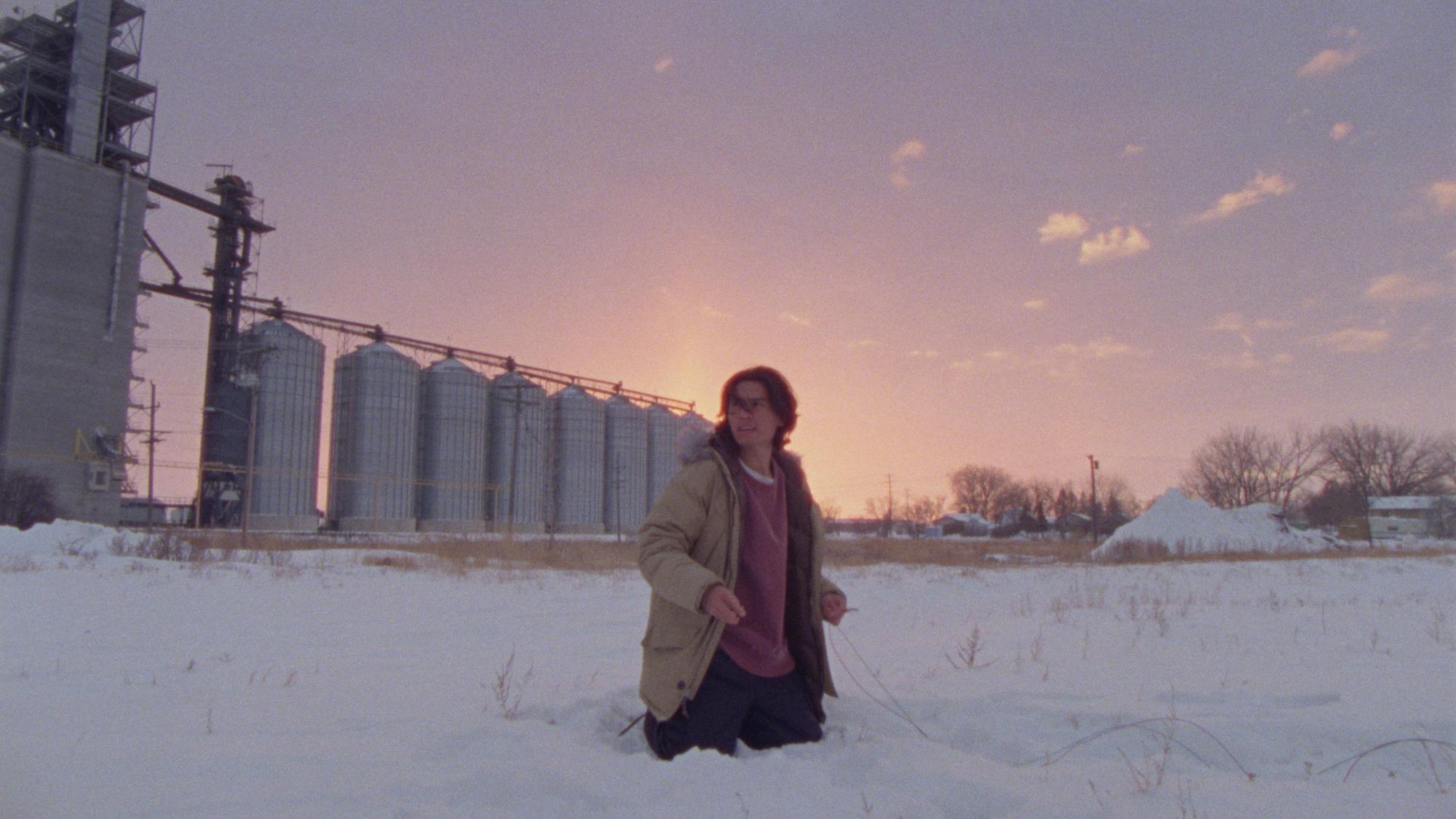 'How to Blow Up a Pipeline' Forrest Goodluck as Michael standing in the snow in front of an oil factory.
