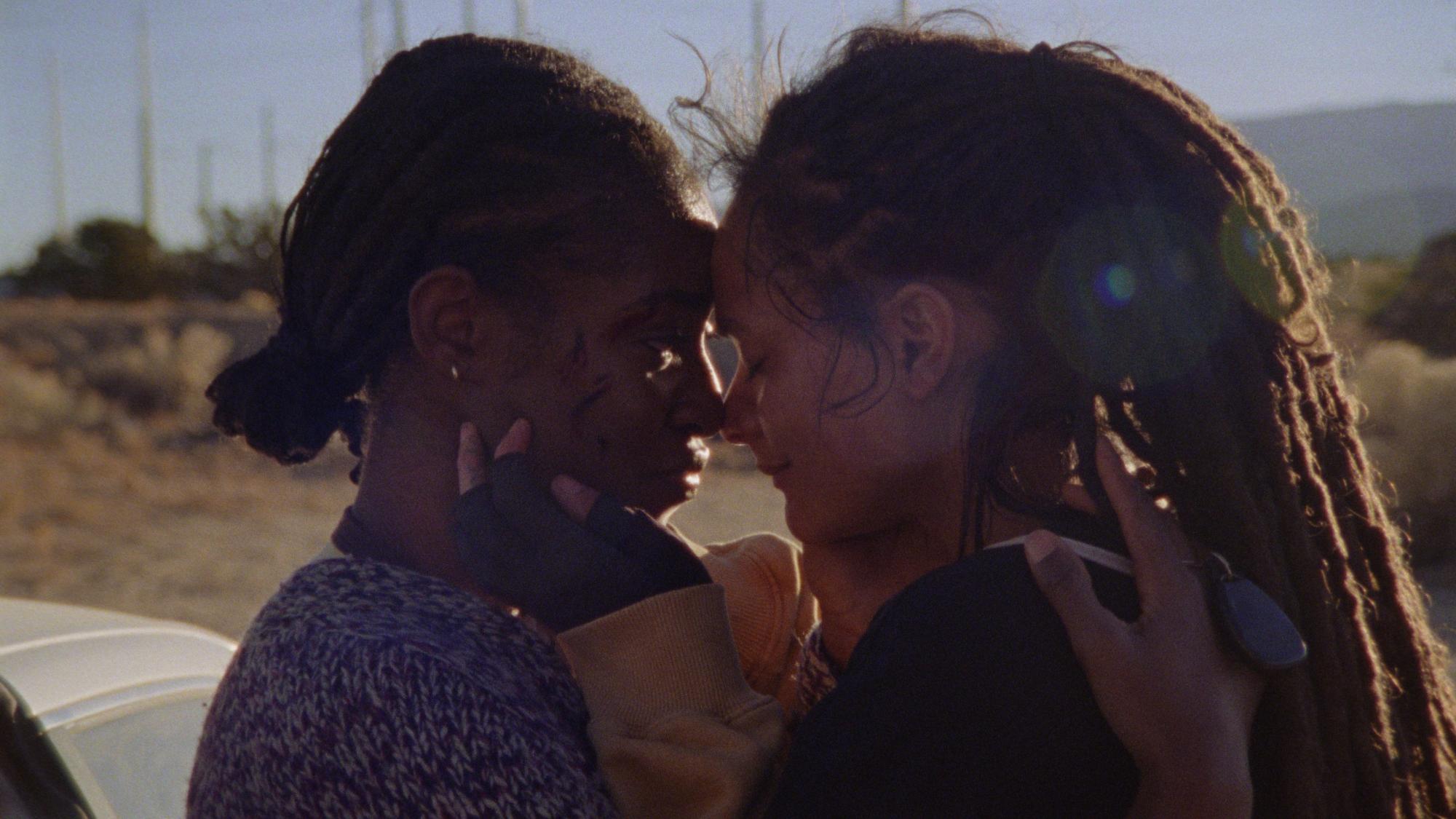 'How to Blow Up a Pipeline' Jayme Lawson as Alisha and Sasha Lane as Theo embracing one another in the desert. Alisha is covered in bruises and cuts.