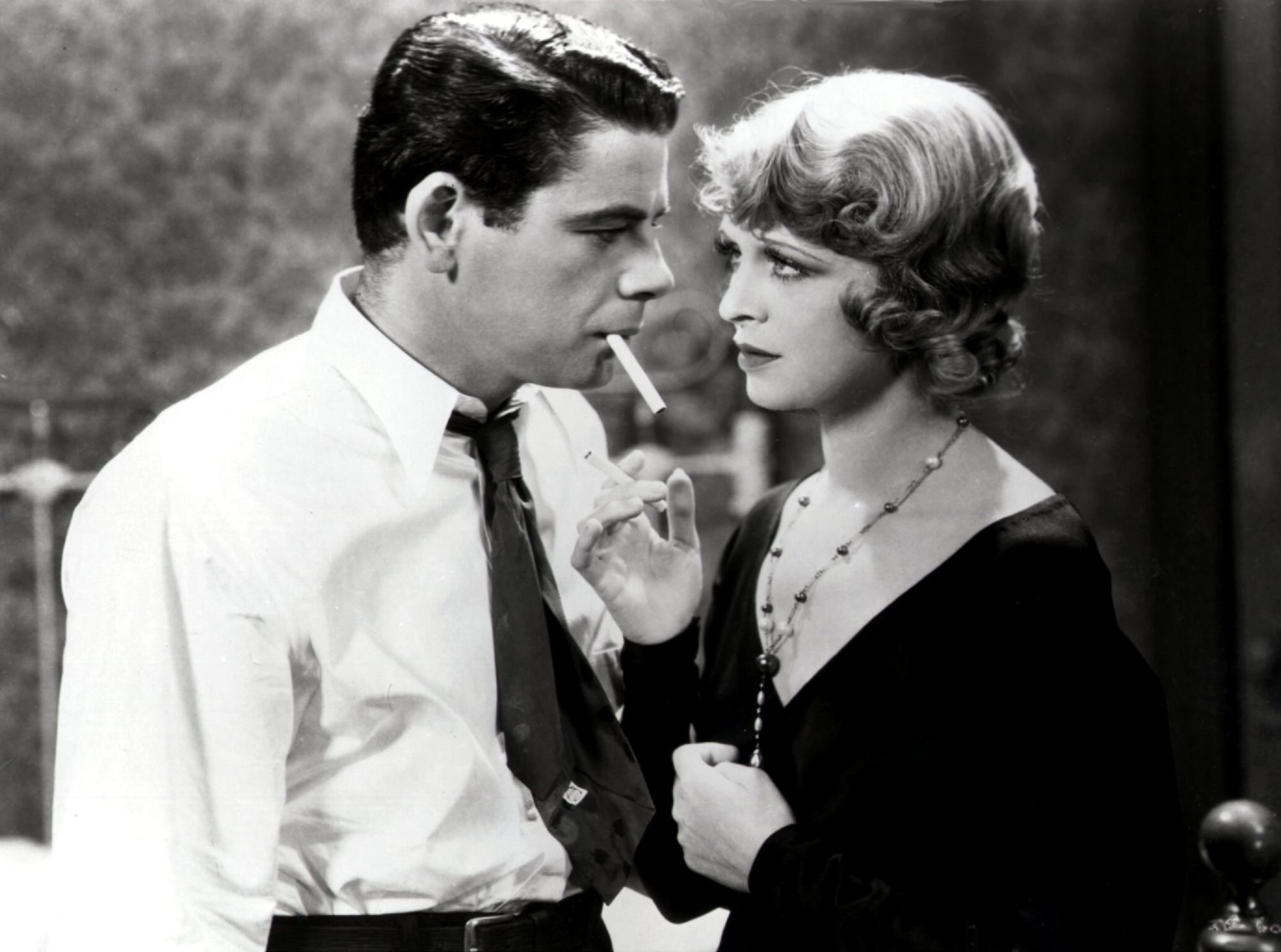 'I Am a Fugitive from a Chain Gang' Paul Muni as James Allen and Noel Francis as Linda. He's wearing a tie and dress shirt, with a cigarette in his mouth. She's looking into his eyes, wearing a necklace and a black dress.