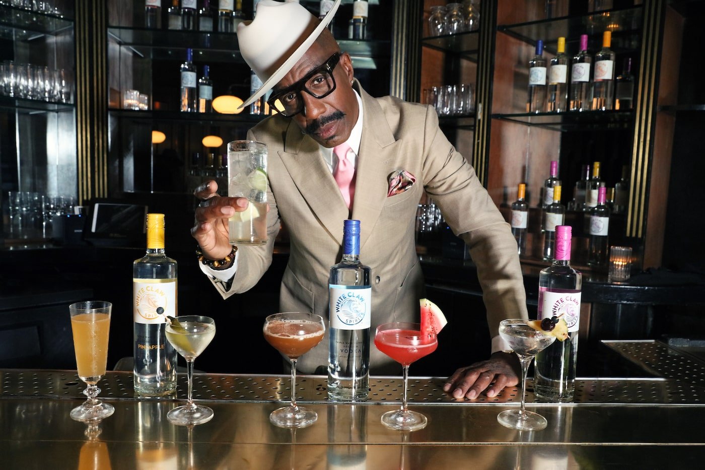 JB Smoove from Curb Your Enthusiasm behind the bar and holds a cocktail 