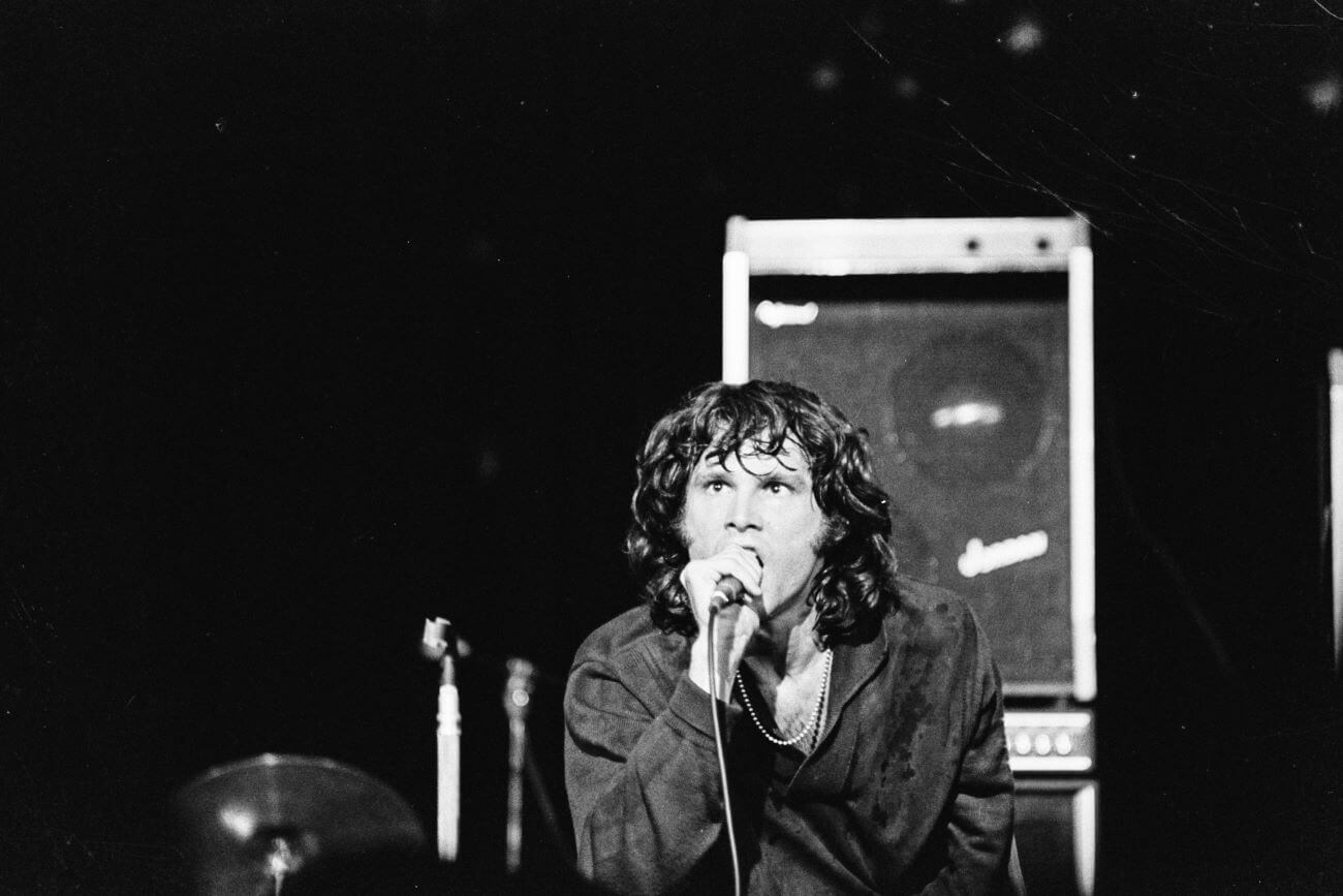 A black and white picture of Jim Morrison singing into a microphone.