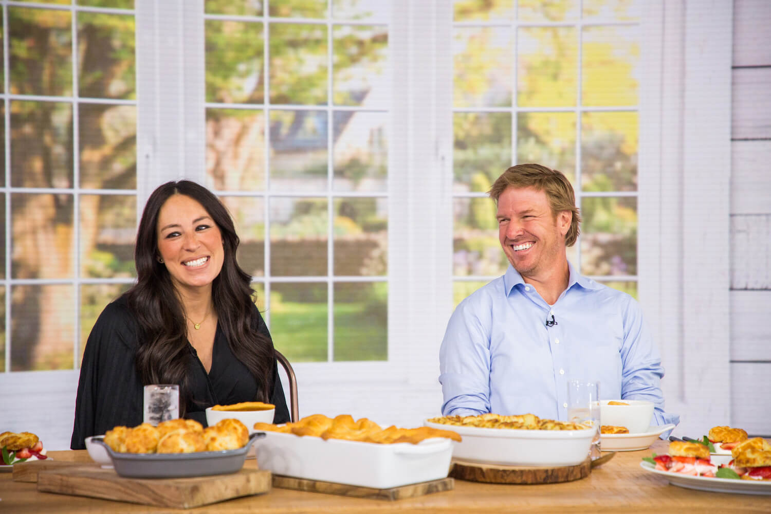 'Fixer Upper' stars Joanna Gaines and Chip Gaines sitting at a table with food