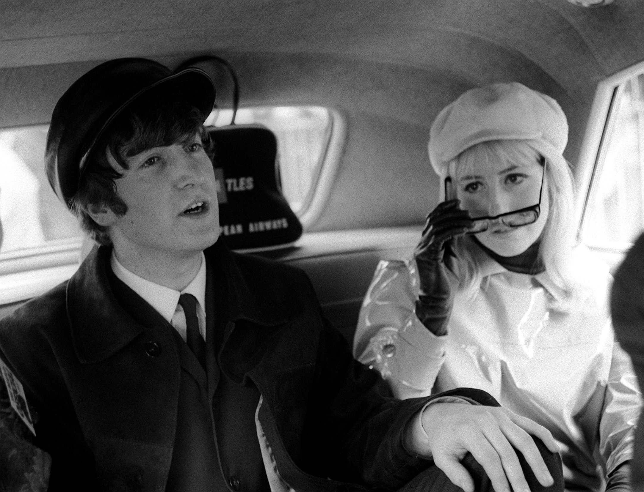 John Lennon and Cynthia Lennon in the back of a car.