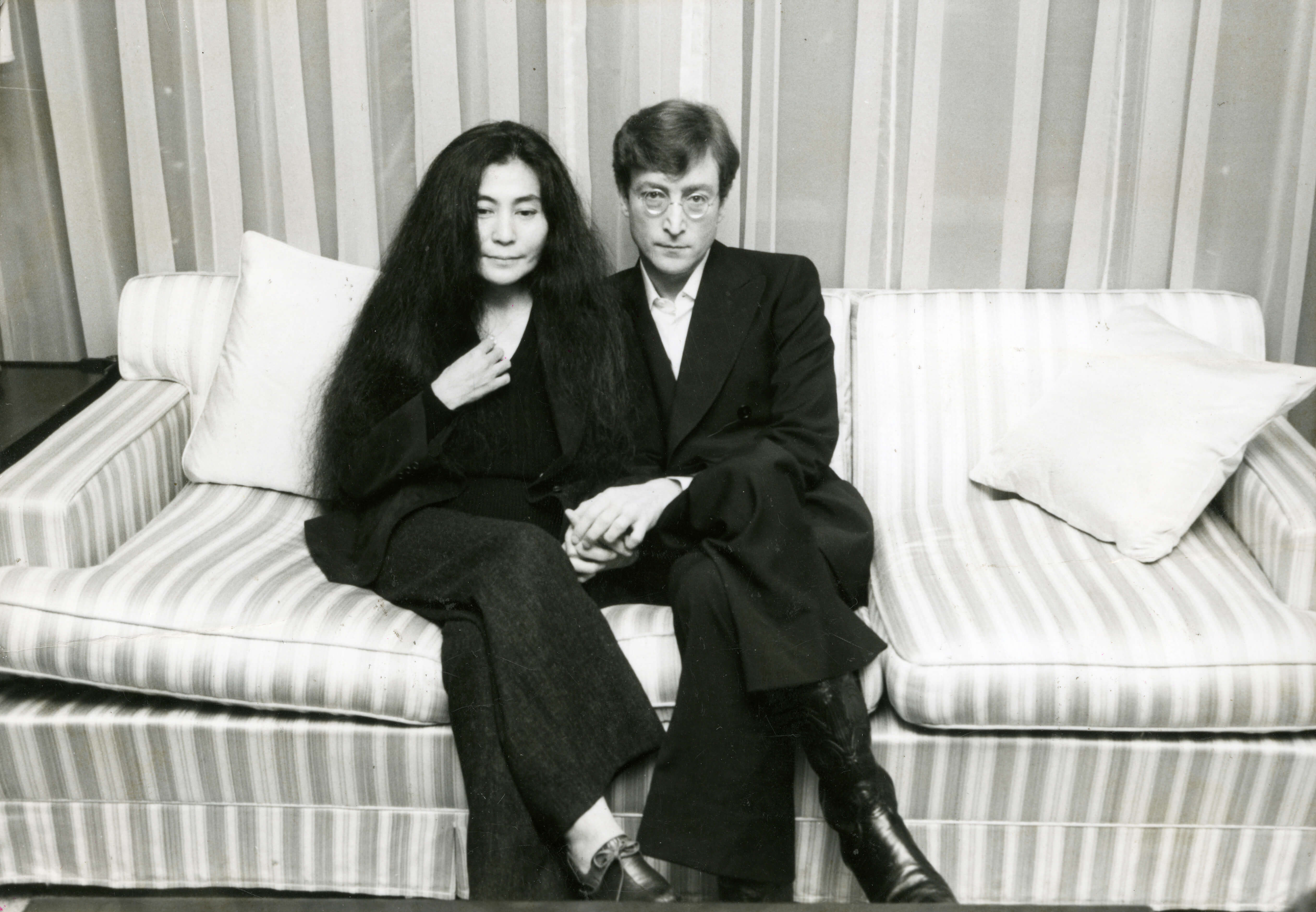 Yoko Ono and John Lennon sit on a couch.
