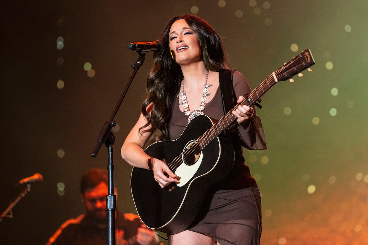 Kacey Musgraves playing a guitar and singing into a microphone