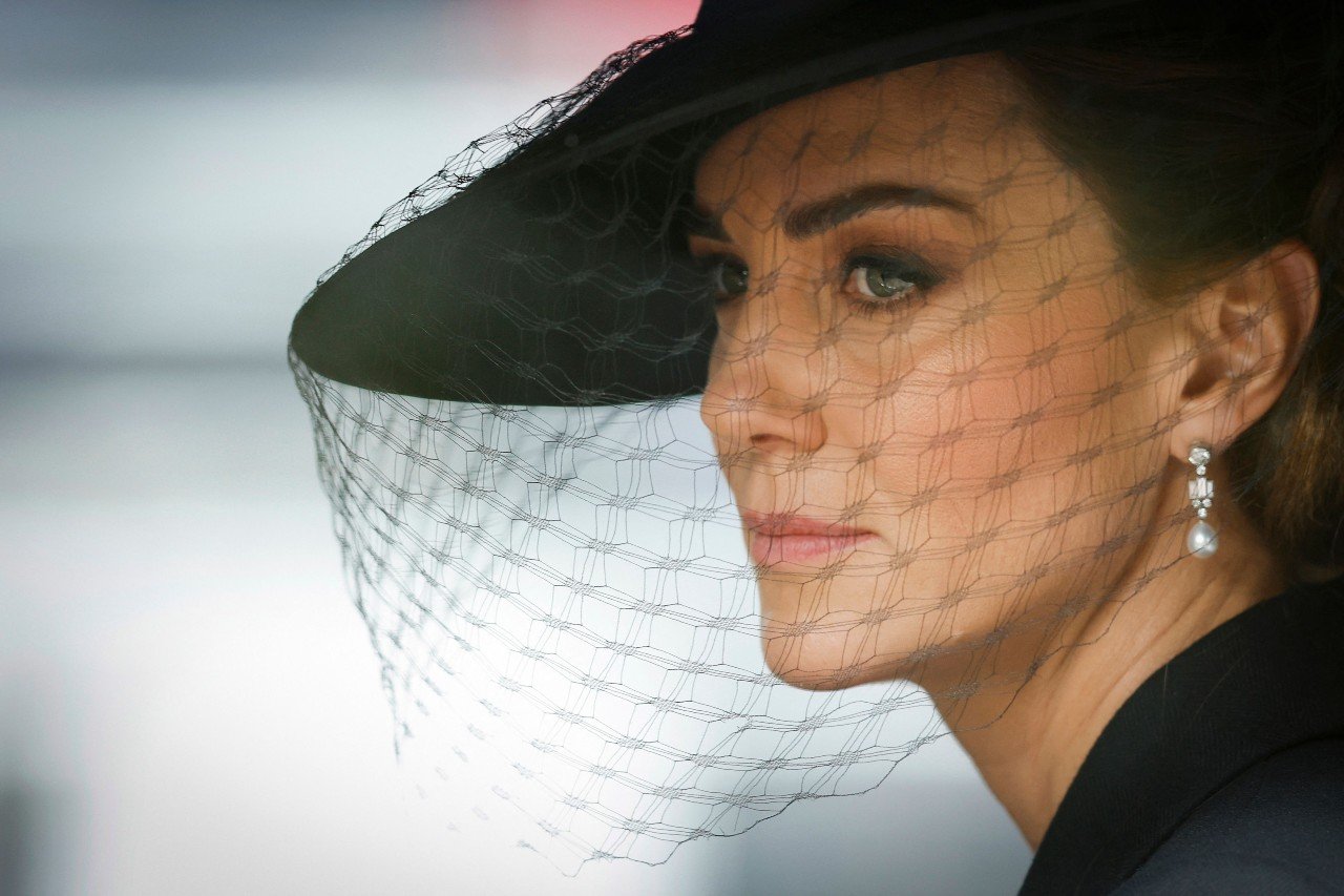 Kate Middleton wears a black hat and veil and looks forlorn during the funeral of Queen Elizabeth III.