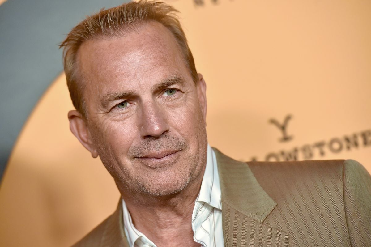 Kevin Costner smiles for a photo in front of a "Yellowstone" backdrop