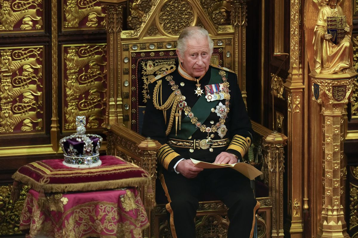 Prince Charles sits next to Queen Elizabeth II's crown. 