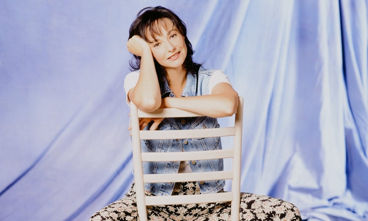 Leila Kenzle sits on a white chair as Fran Devanow for a promotional shot for 'Mad About You'