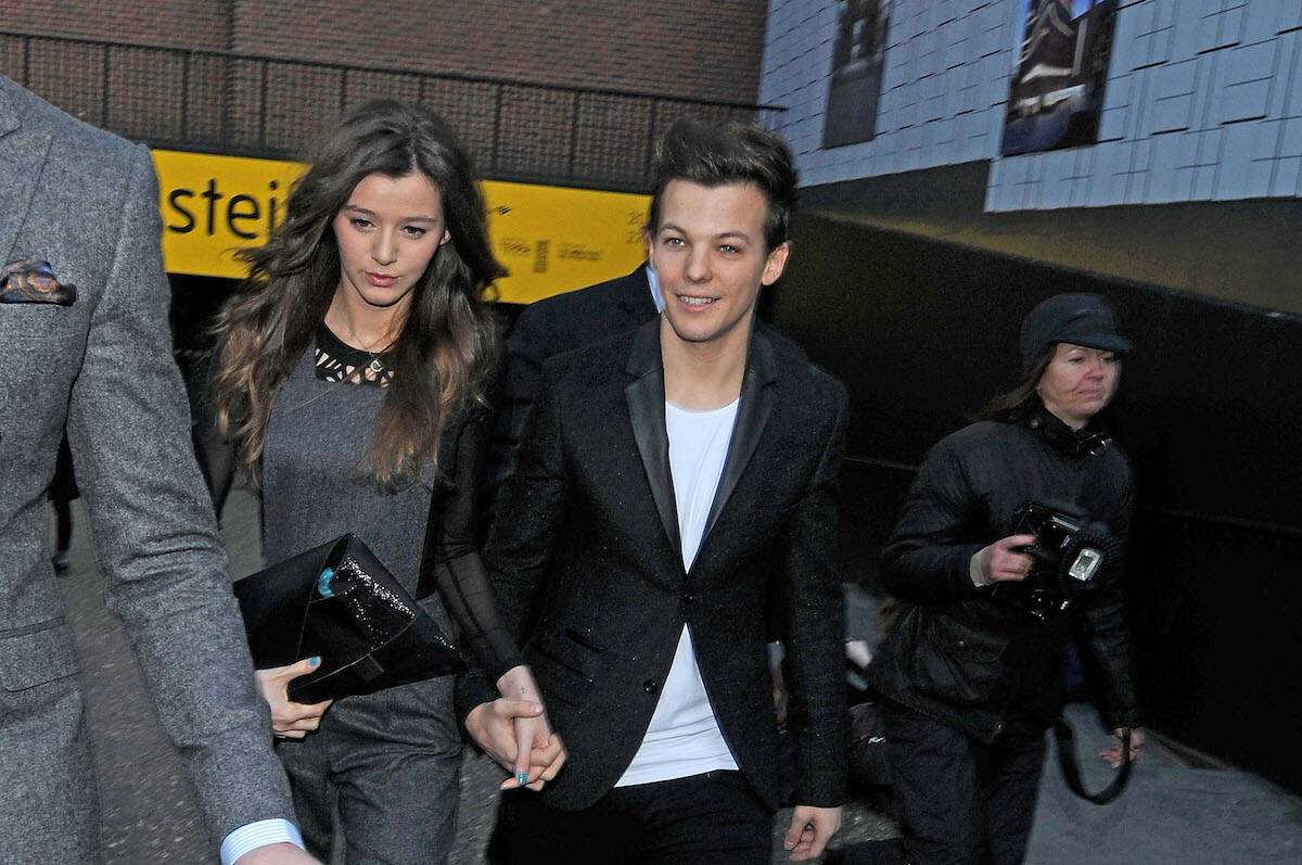 Louis Tomlinson and Eleanor Calder walk past paparazzi together in 2013
