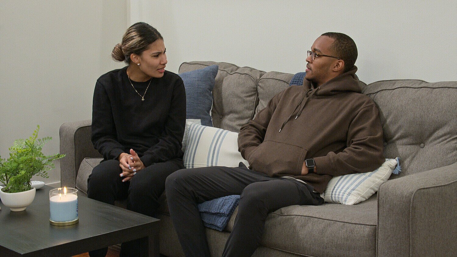 'Love Is Blind' stars Marshall and JAckie sit on a gray couch together while having a conversation.