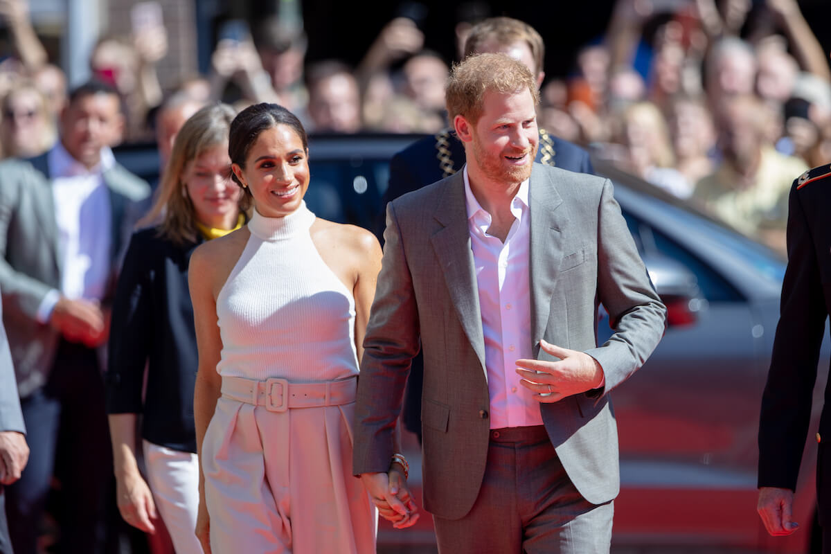Meghan Markle and Prince Harry smiling, holding hands
