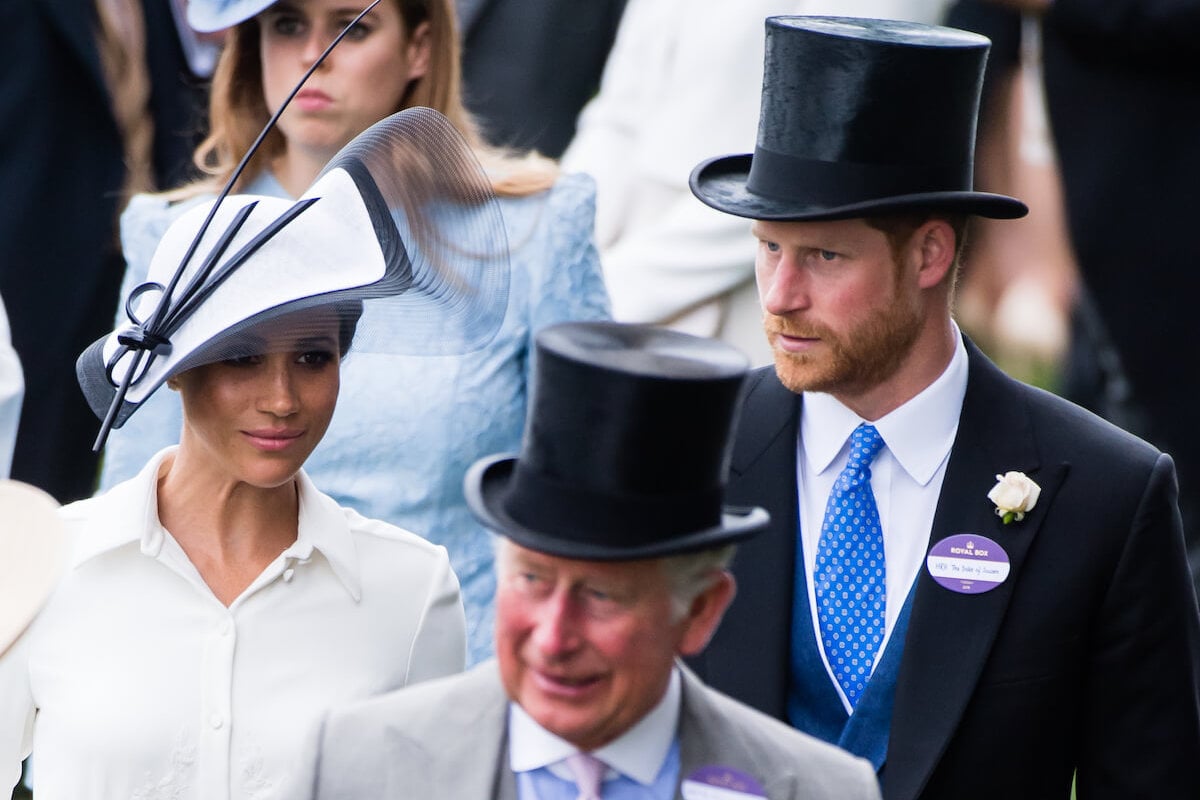 Meghan Markle and Prince Harry, whom a commentator says may have already RSVPd to the coronation, walk behind King Charles III