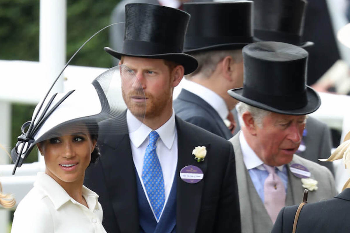 Prince Harry, who is attending the coronation alone but should bring Prince Archie and Princess Lilibet, according to an author, stands with Meghan Markle and King Charles III