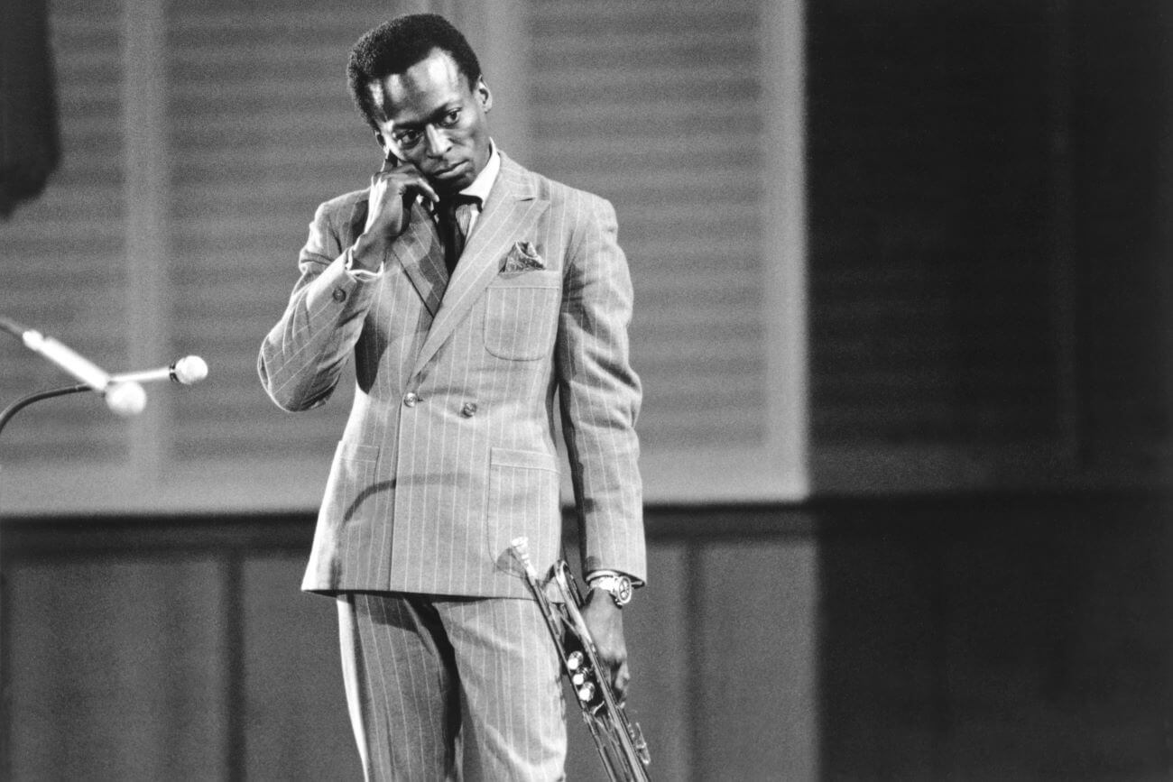 A black and white picture of Miles Davis holding a trumpet.