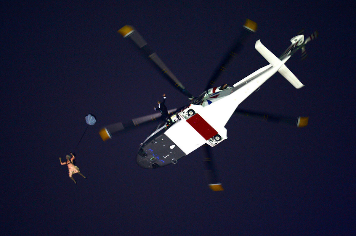 Performerrs jump out of a helicopter as part of James Bond video introduction for Queen Elizabeth at the 2012 Olympic Games