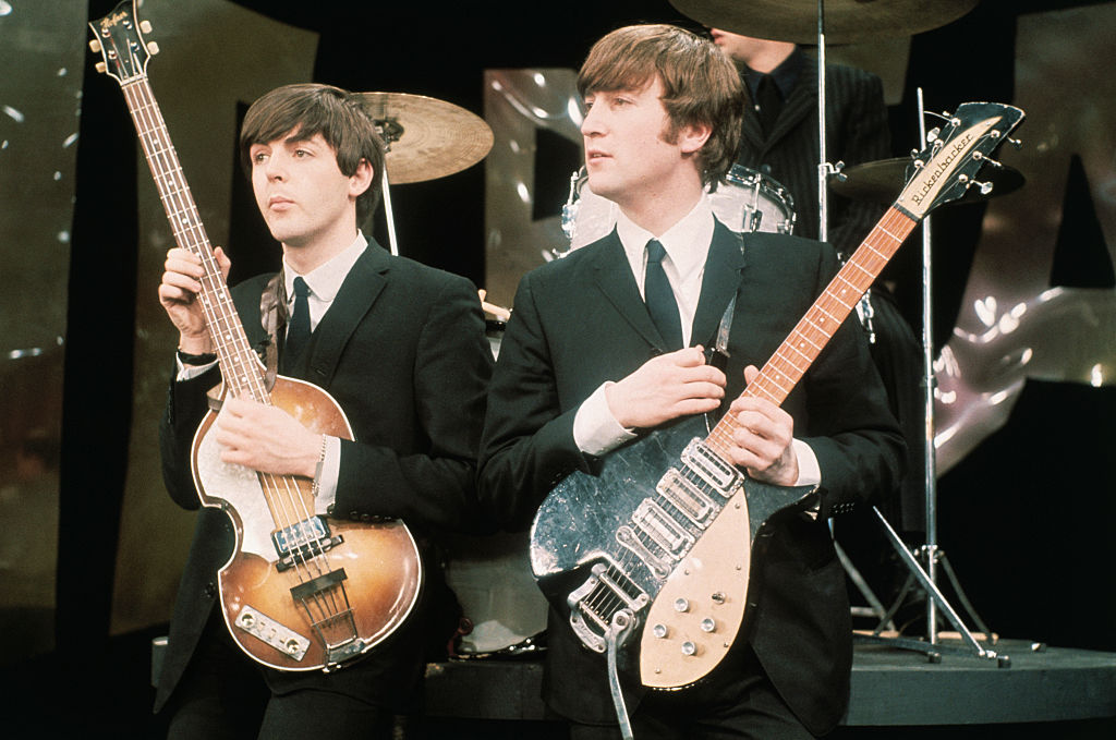 Paul McCartney and John Lennon stand with their guitars. 