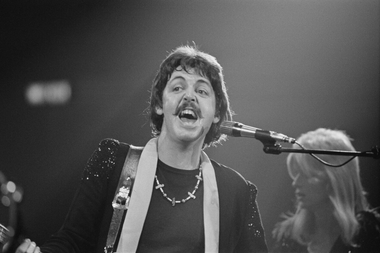 Paul McCartney sings during a 1976 Wings concert while Linda McCartney stands behind him.
