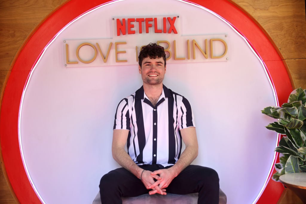 Paul of 'Love Is Blind' sits in front of a Netflix sign.