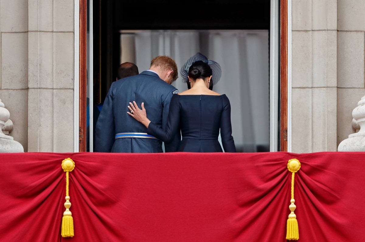 Prince Harry and Meghan Markle walk back inside Buckingham Palace after watching a flypast on the balcony