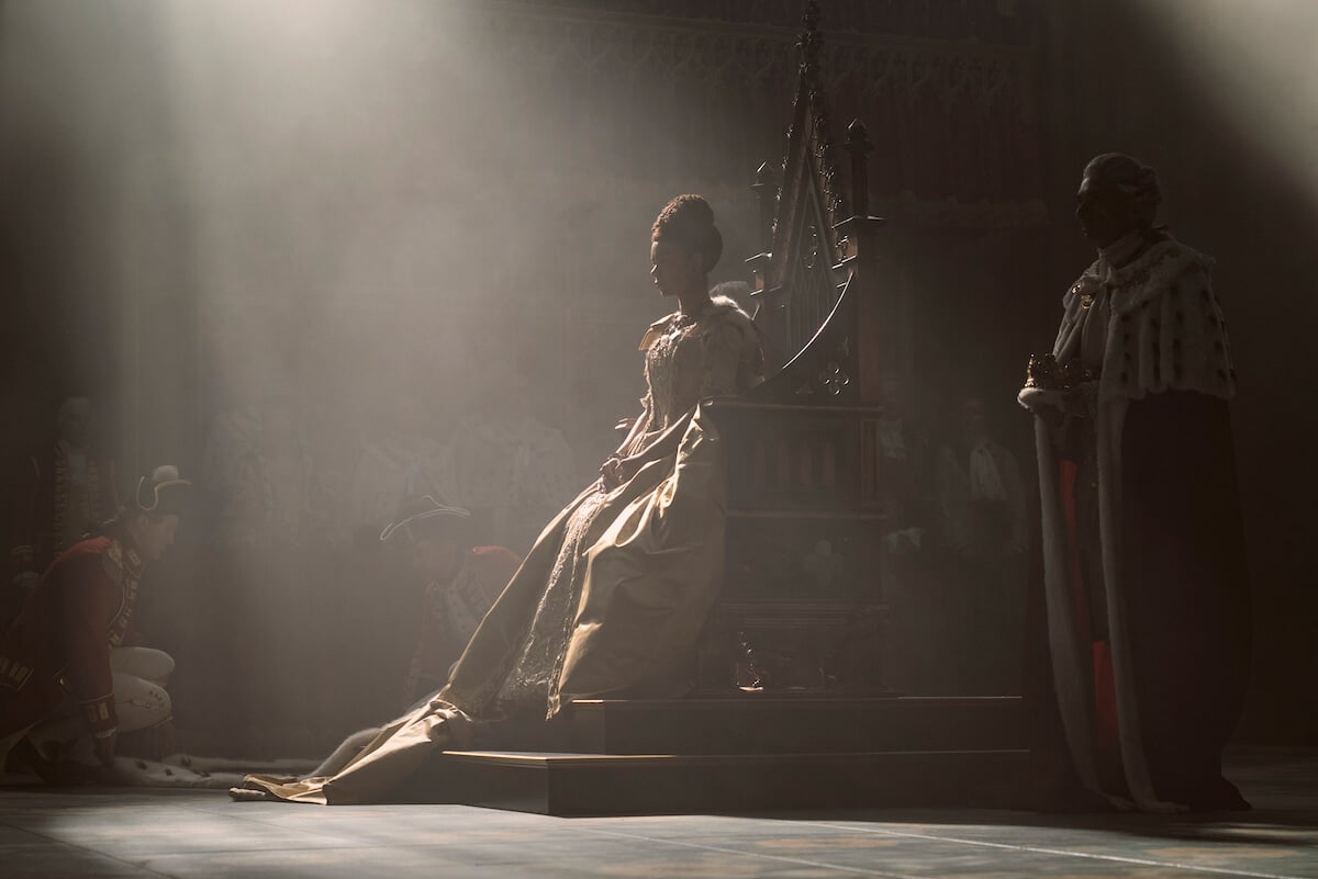 India Amarteifio as Queen Charlotte sitting on a throne in the dark in 'Queen Charlotte: A Bridgerton Story'
