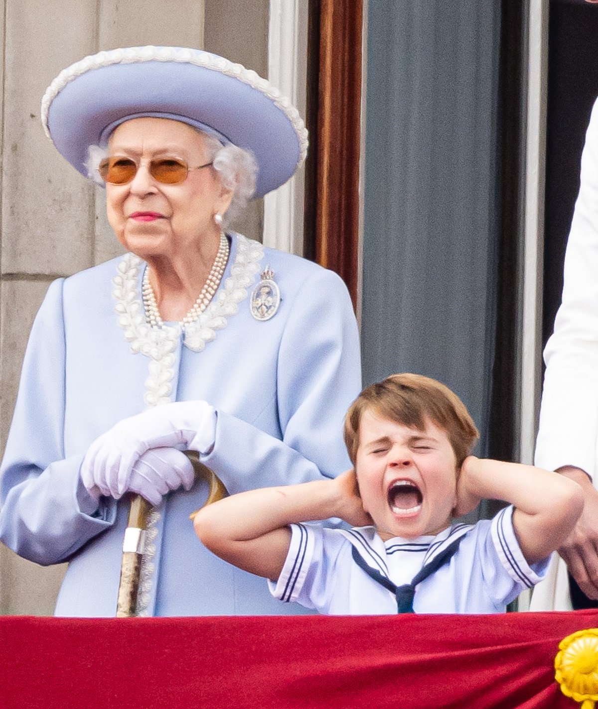 Queen Elizabeth II standing next to Prince Louis who is covering his ears during Trooping the Colour 2022