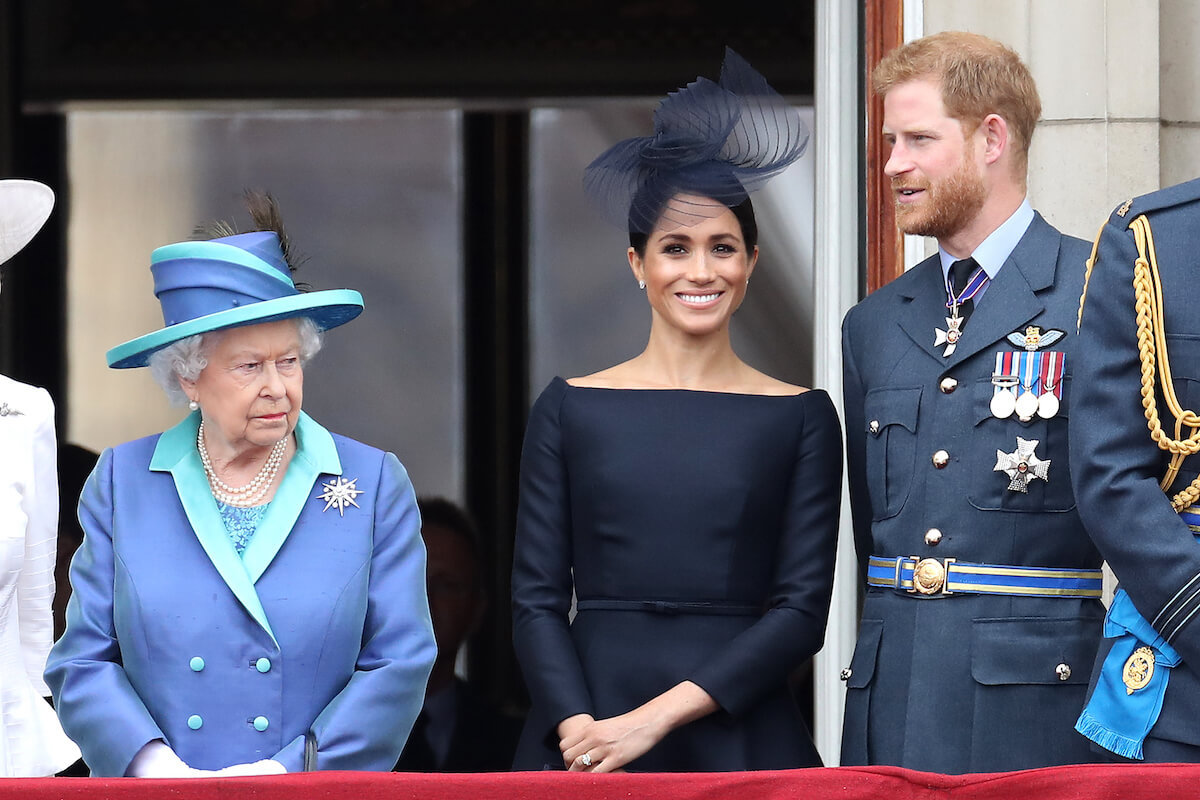 Queen Elizabeth II, who wasn't 'surprised' by Meghan Markle's three-word rejection of advice, according to Robert Jobson's 'Our King' book, stands with Meghan Markle and Prince Harry