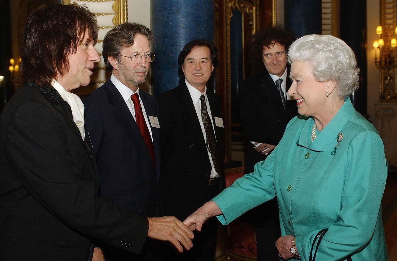 Queen Elizabeth II shakes hands with Jeff Beck while Eric Clapton, Jimmy Page, and Brian May look on.