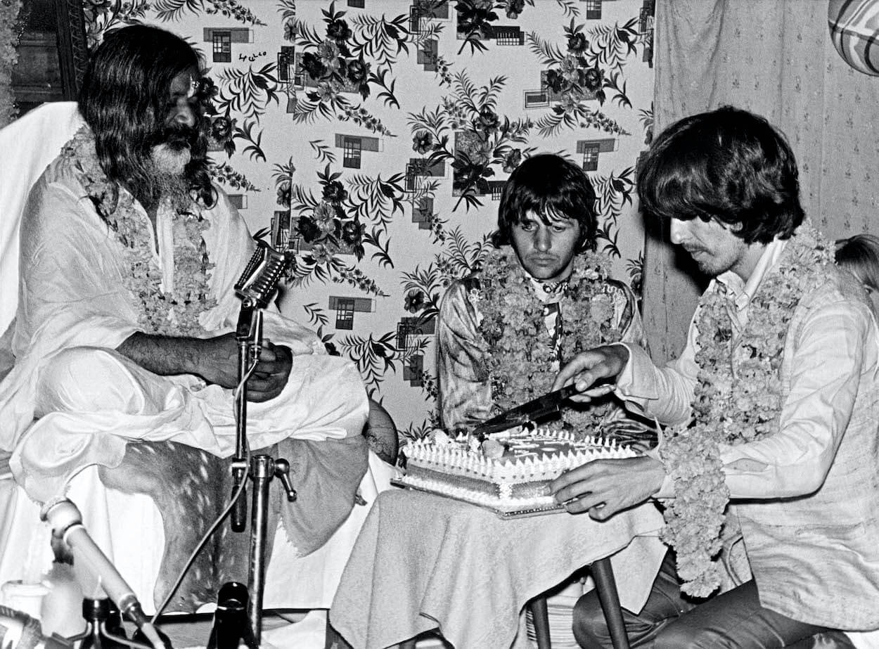George Harrison (right) cuts a cake as Maharishi Mahesh Yogi and Ringo Starr (center) celebrate George's 25th birthday in India in February 1968.